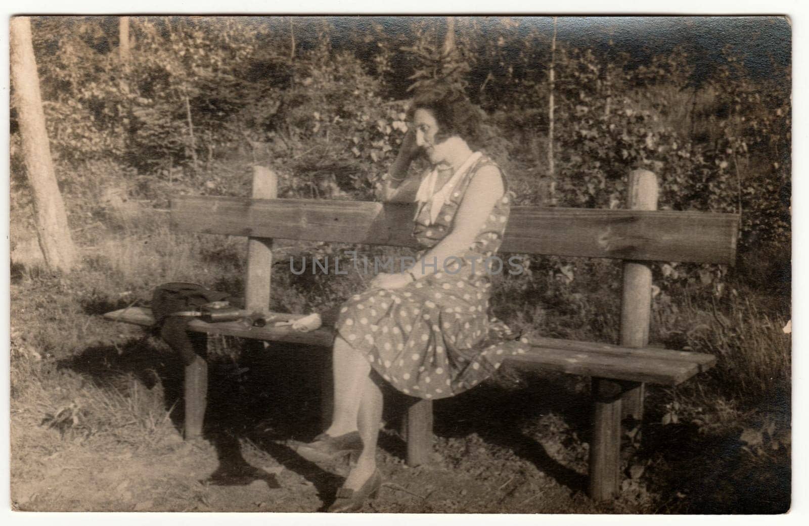 Vintage photo shows woman sits on the wooden bench in the park. Retro black and white photography. Circa 1930s. by roman_nerud