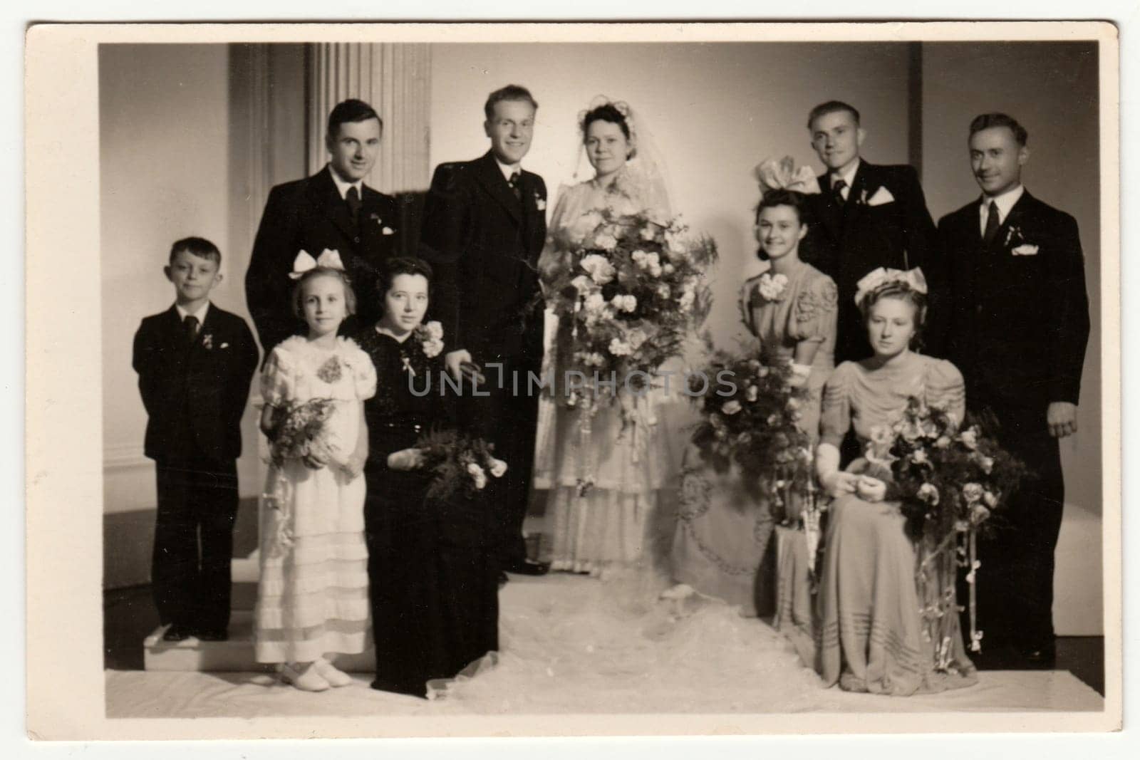 Vintage photo shows newlyweds, bridesmaids, bridesmen and other wedding guests. Retro black and white photography. Circa 1950s. by roman_nerud