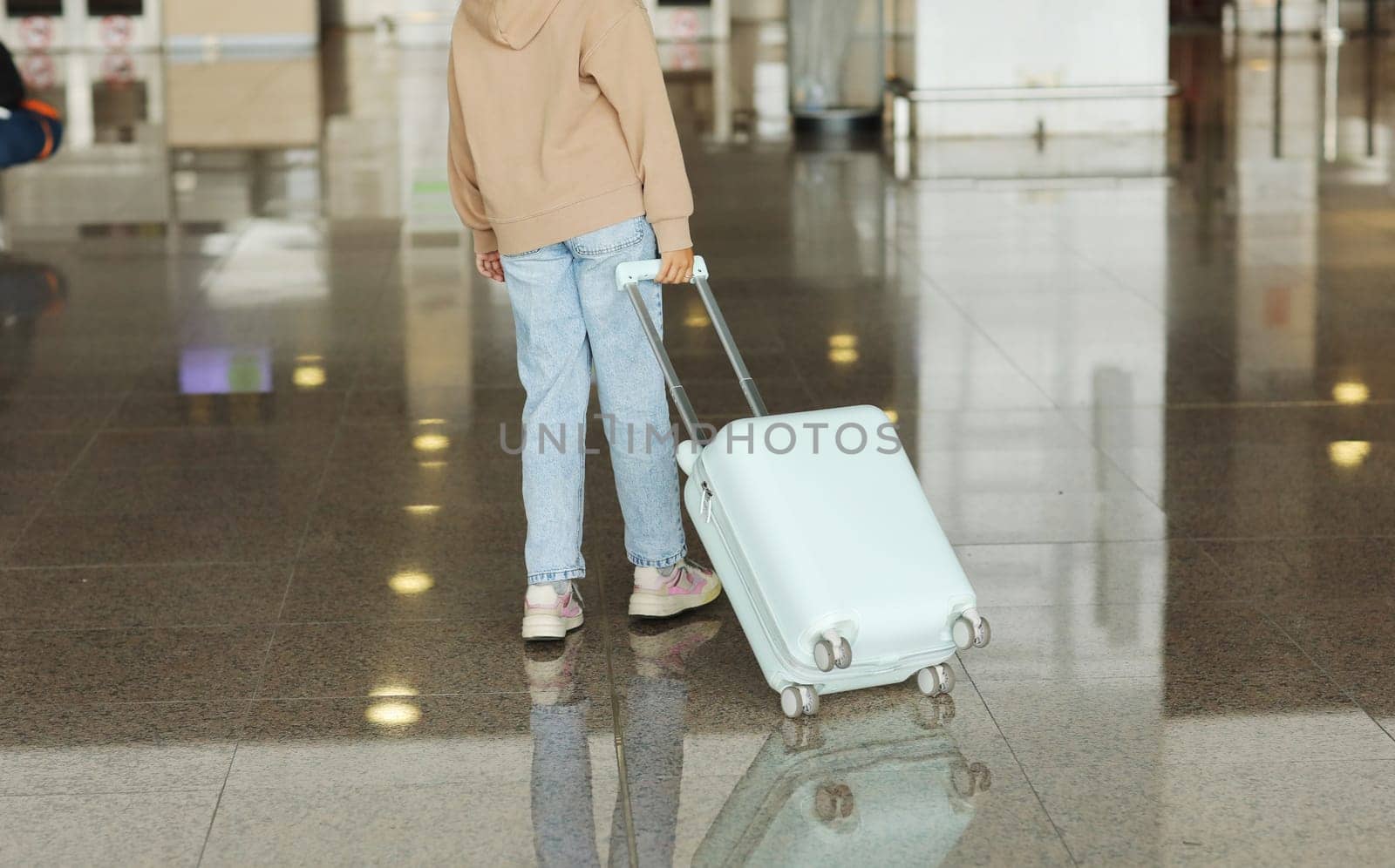 Traveling with children. cropped photo of cute teenage girl walking together with travel suitcase in airport. cute child girl goes on trip abroad on weekends