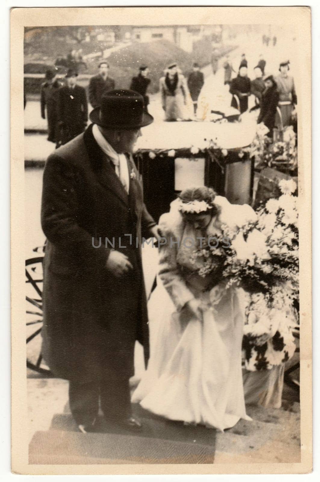 Vintage photo shows a groom - bridegroom and bride. A historical carriage - coach is on the background. Retro black and white photography. Circa 1940s. by roman_nerud