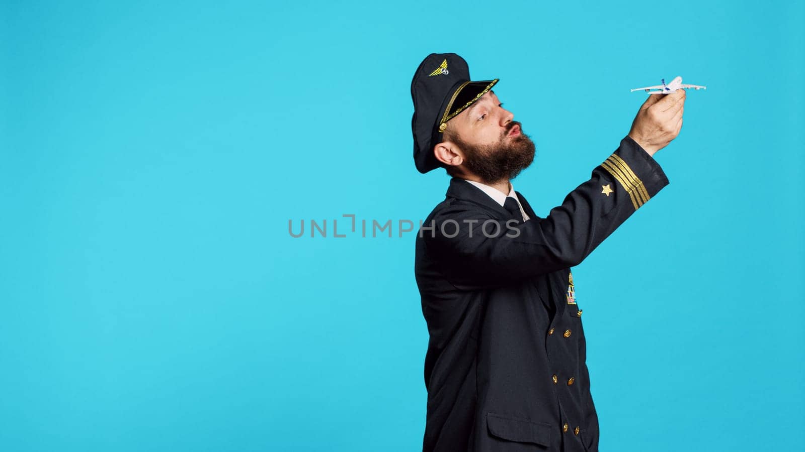 Caucasian man dressed as pilot playing with airplane toy by DCStudio