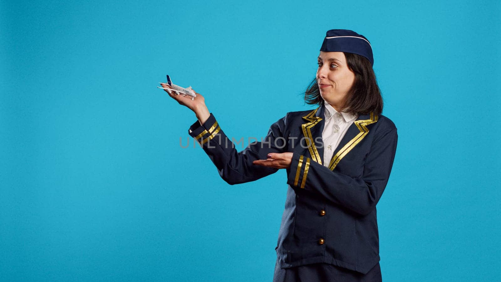 Smiling stewardess showing artificial plane toy by DCStudio