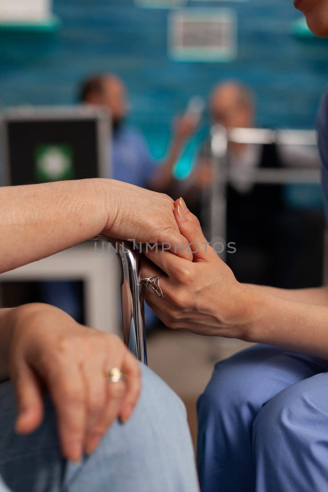 Nurse holding hand of an elderly patient in wheelchair, giving support and motivation in difficult moments. Professional nurses specialized in nursing home care for seniors.