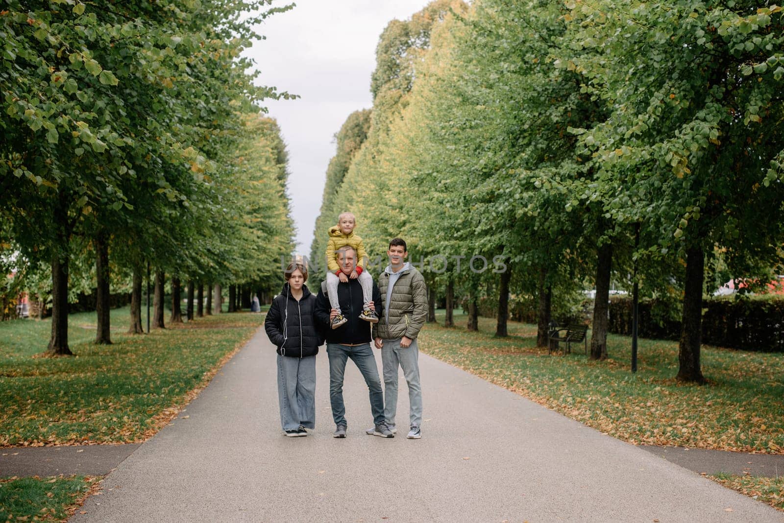 Happy family - Father with three children together in autumn park. Making it a day of fun. Parents spending time with their children outside. by Andrii_Ko