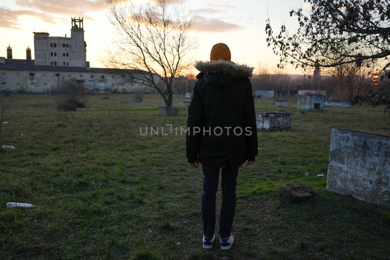 Tall guy standing looking at a scary old building alone in distance. High quality photo
