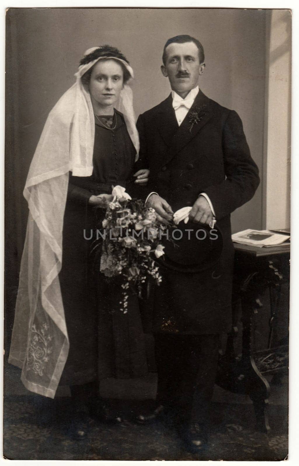 PRAHA (PRAGUE), THE CZECHOSLOVAK REPUBLIC - CIRCA 1921: Vintage photo shows newlyweds. The bride wears long white veil. Retro black and white studio photography of married couple. Vintage photo shows the road in the village. Retro black and white photography. Circa 1920s.