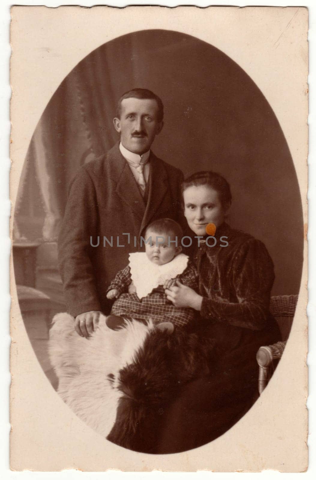 PRAHA - PRAGUE, THE CZECHOSLOVAK REPUBLIC - CIRCA 1923: Vintage photo shows family - father, mother and baby boy. Retro black and white studio photography of a bourgeois family. Vintage photo shows the road in the village. Retro black and white photography. Circa 1920s.