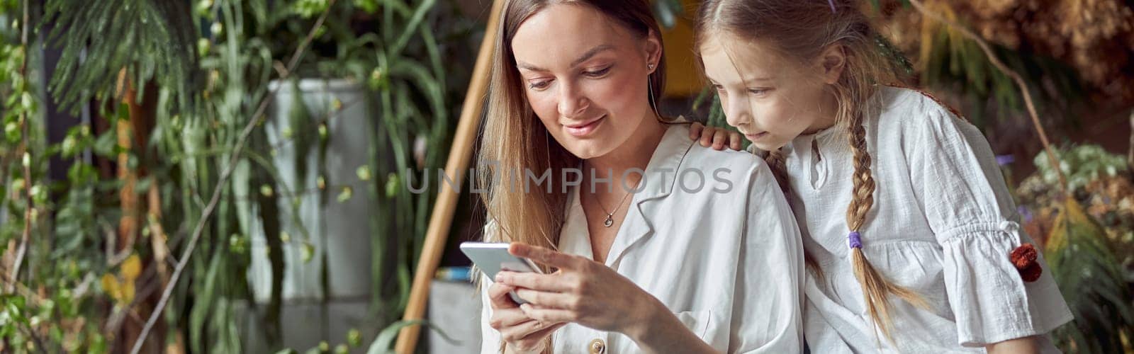 Flourist shop with different kinds of dryed flowers. Young happy confident specialist is working with her female kid. by Yaroslav_astakhov