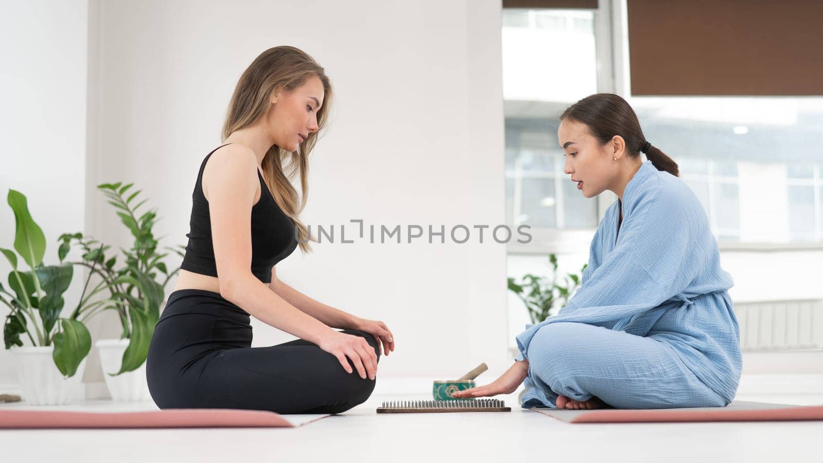 Caucasian and Asian women getting ready to stand on sadhu boards