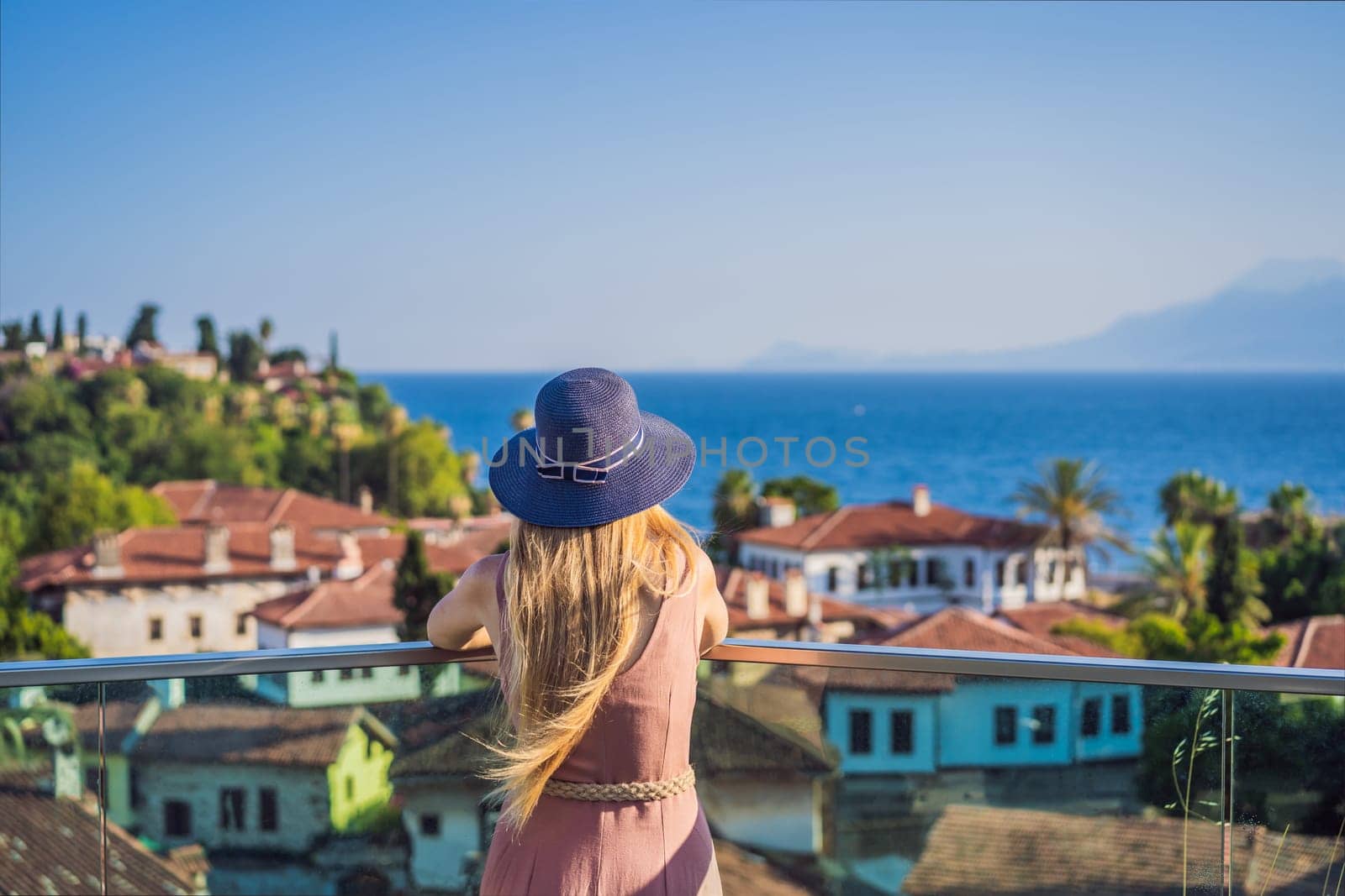 Woman tourist in Old town Kaleici in Antalya. Turkiye. Panoramic view of Antalya Old Town port, Taurus mountains and Mediterrranean Sea, Turkey.