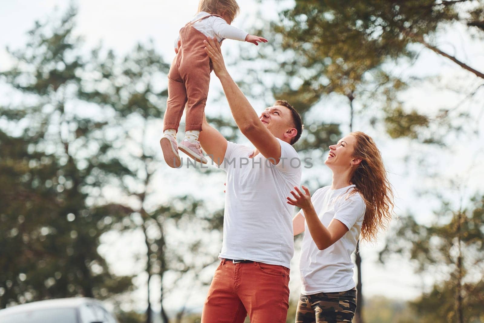 Father and mother spending weekend outdoors near forest with daughter by Standret