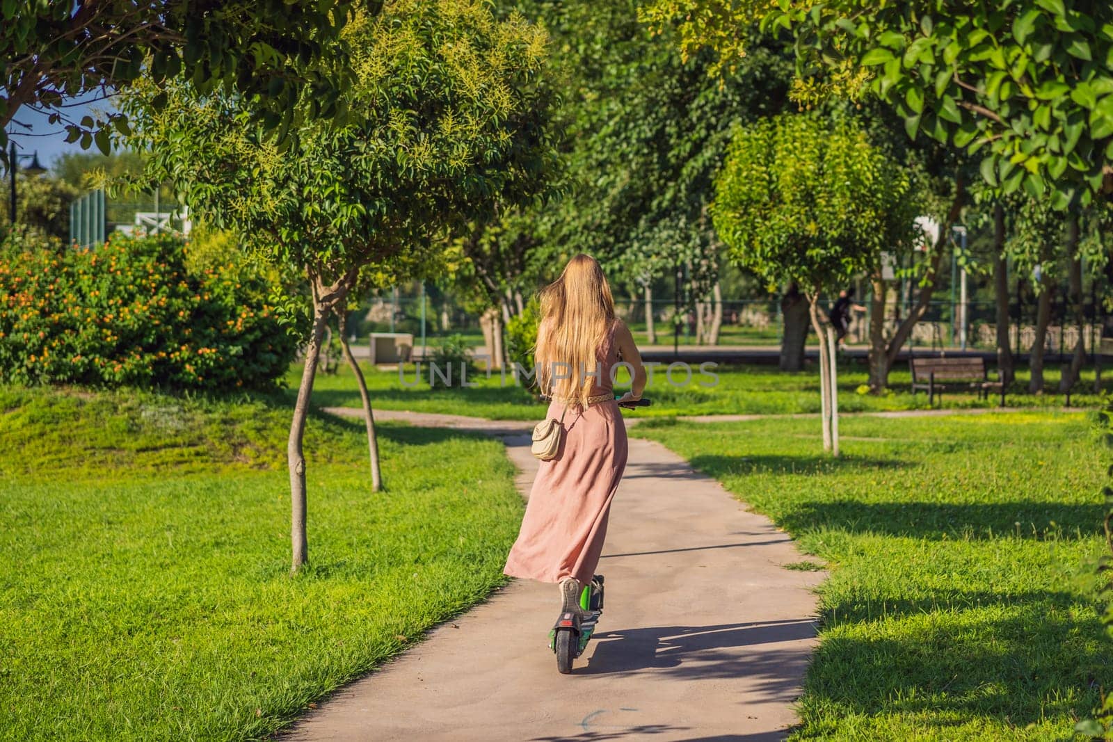 Young beautiful woman riding an electric scooter to work, modern girl, new generation, electric transport, ecology, ecological transport, sunset, electric skateboard.