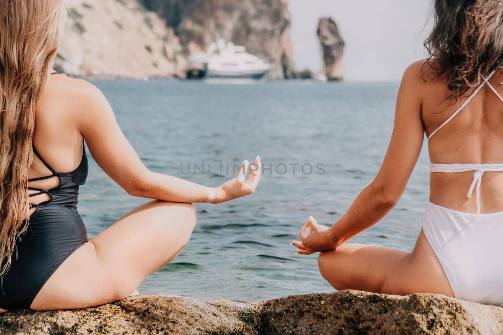 Woman sea yoga. Happy women meditating in yoga pose on the beach, ocean and rock mountains. Motivation and inspirational fit and exercising. Healthy lifestyle outdoors in nature, fitness concept. by panophotograph