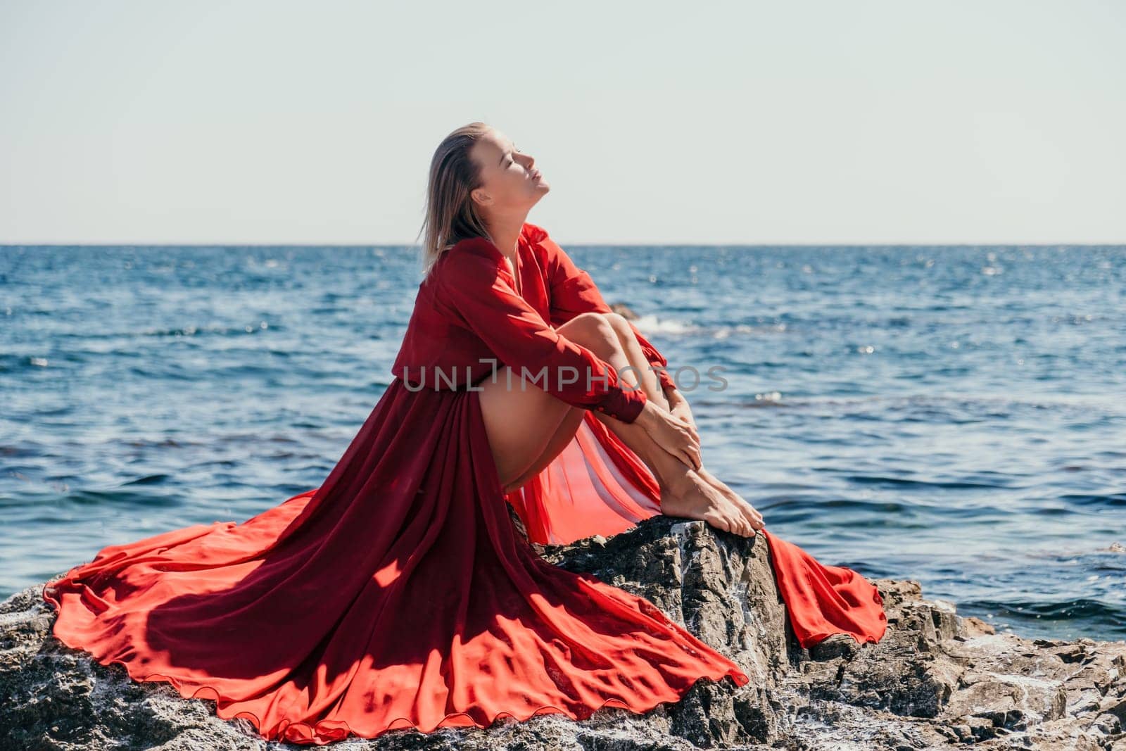 Woman travel sea. Happy tourist in long red dress enjoy taking picture outdoors for memories. Woman traveler posing on beach at sea surrounded by volcanic mountains, sharing travel adventure journey by panophotograph