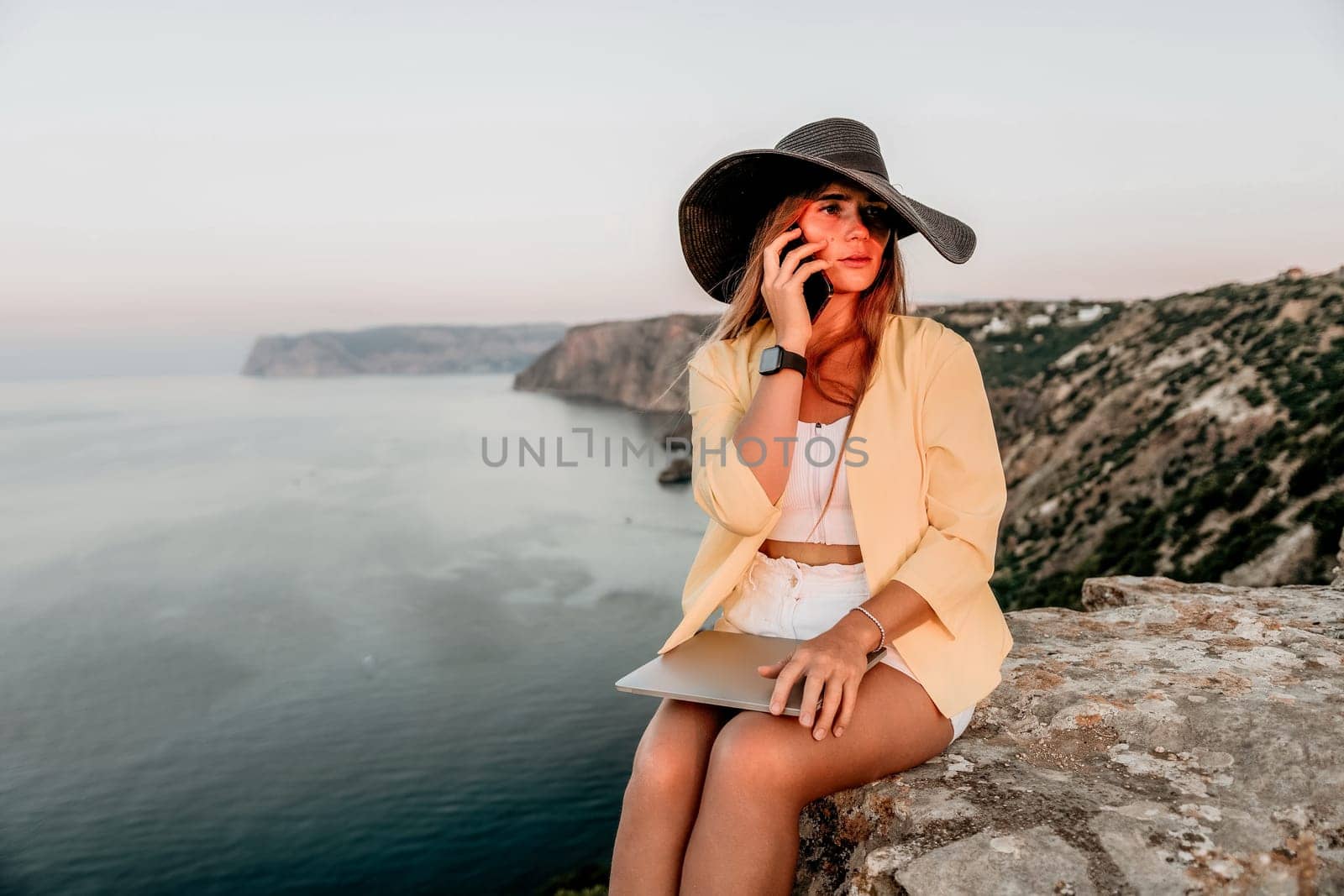 Digital nomad, Business woman working on laptop by the sea. Pretty lady typing on computer by the sea at sunset, makes a business transaction online from a distance. Freelance, remote work on vacation by panophotograph