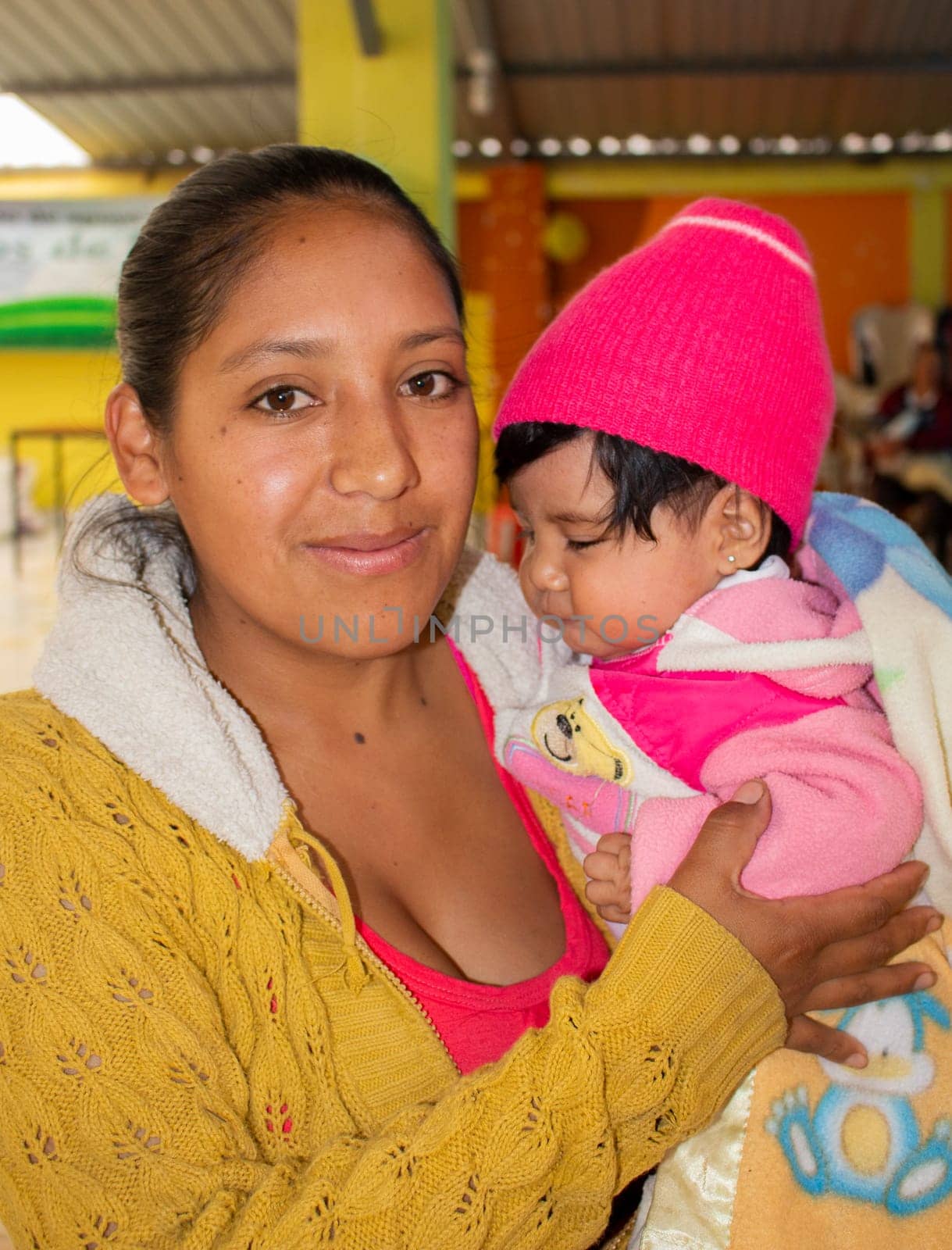 young latino mom with her baby in her arm very happy by Raulmartin