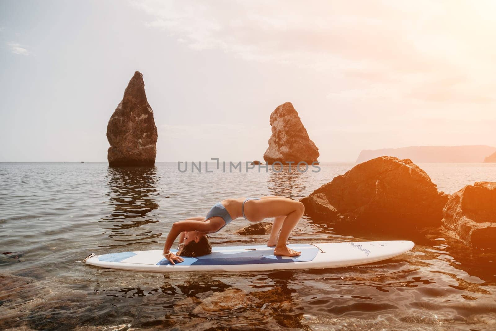 Woman sup yoga. Middle age sporty woman practising yoga pilates on paddle sup surfboard. Female stretching doing workout on sea water. Modern individual hipster outdoor summer sport activity