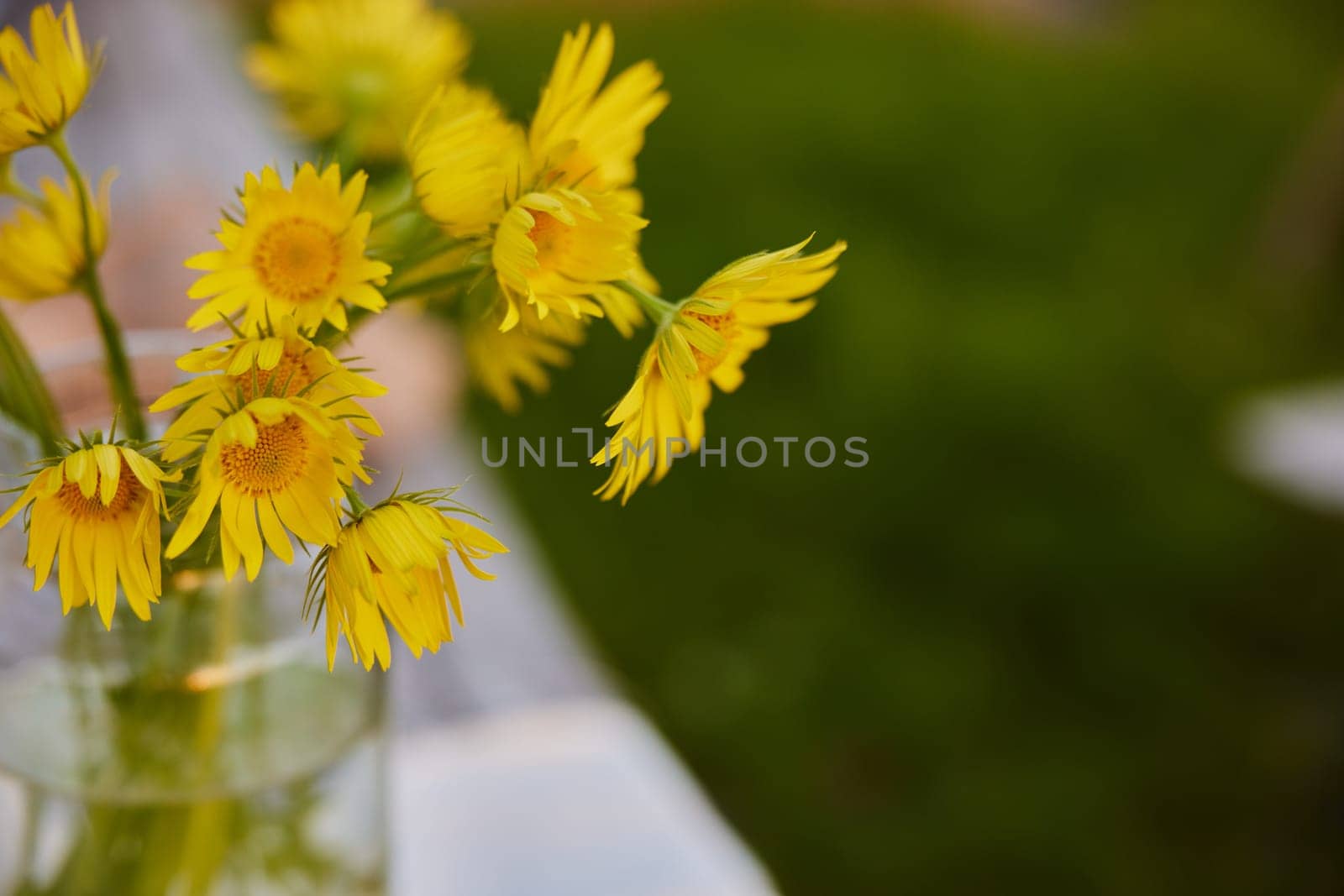 yellow wild flowers stand in a transparent vase on the street. High quality photo