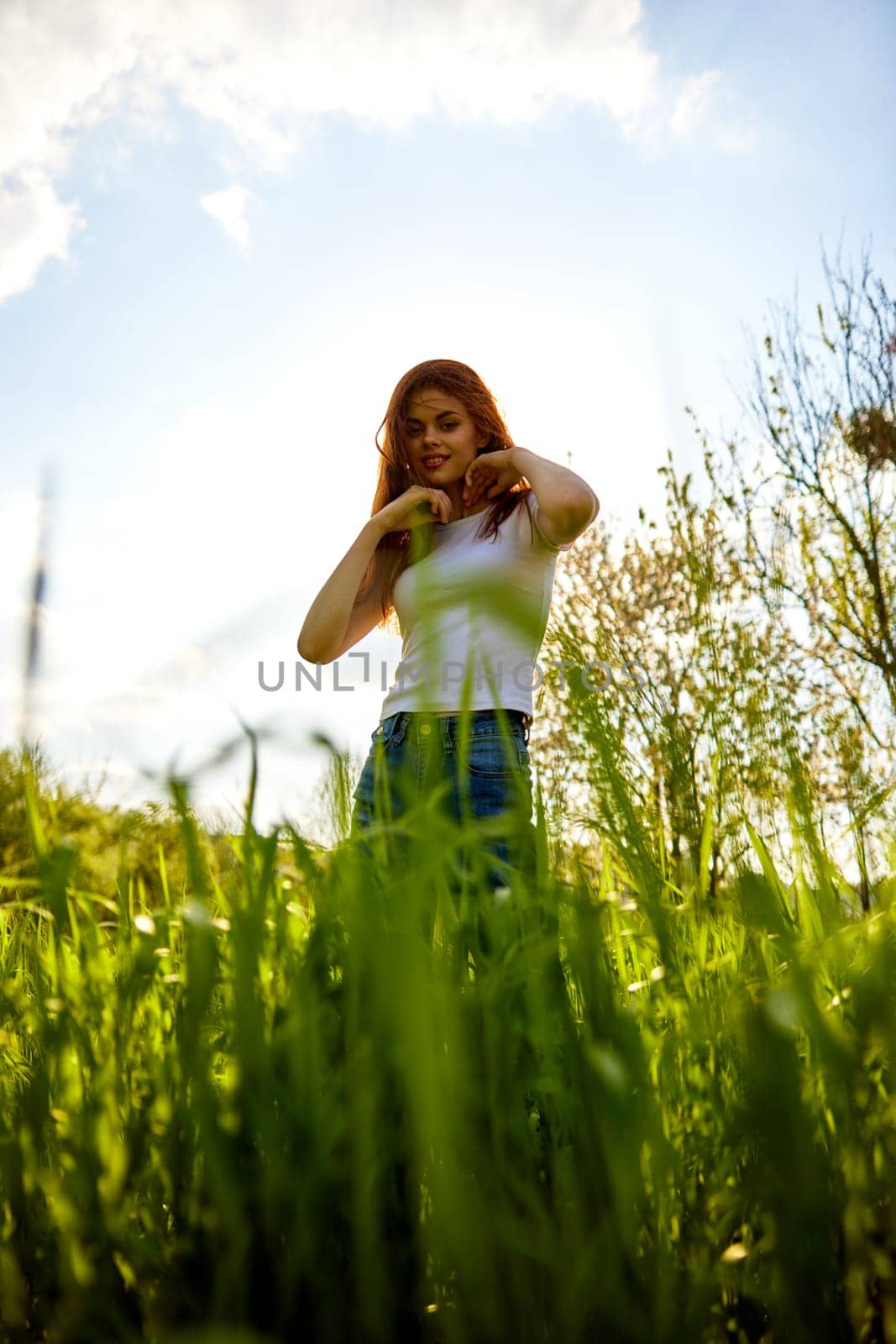 joyful woman posing in tall grass on a sunny day by Vichizh