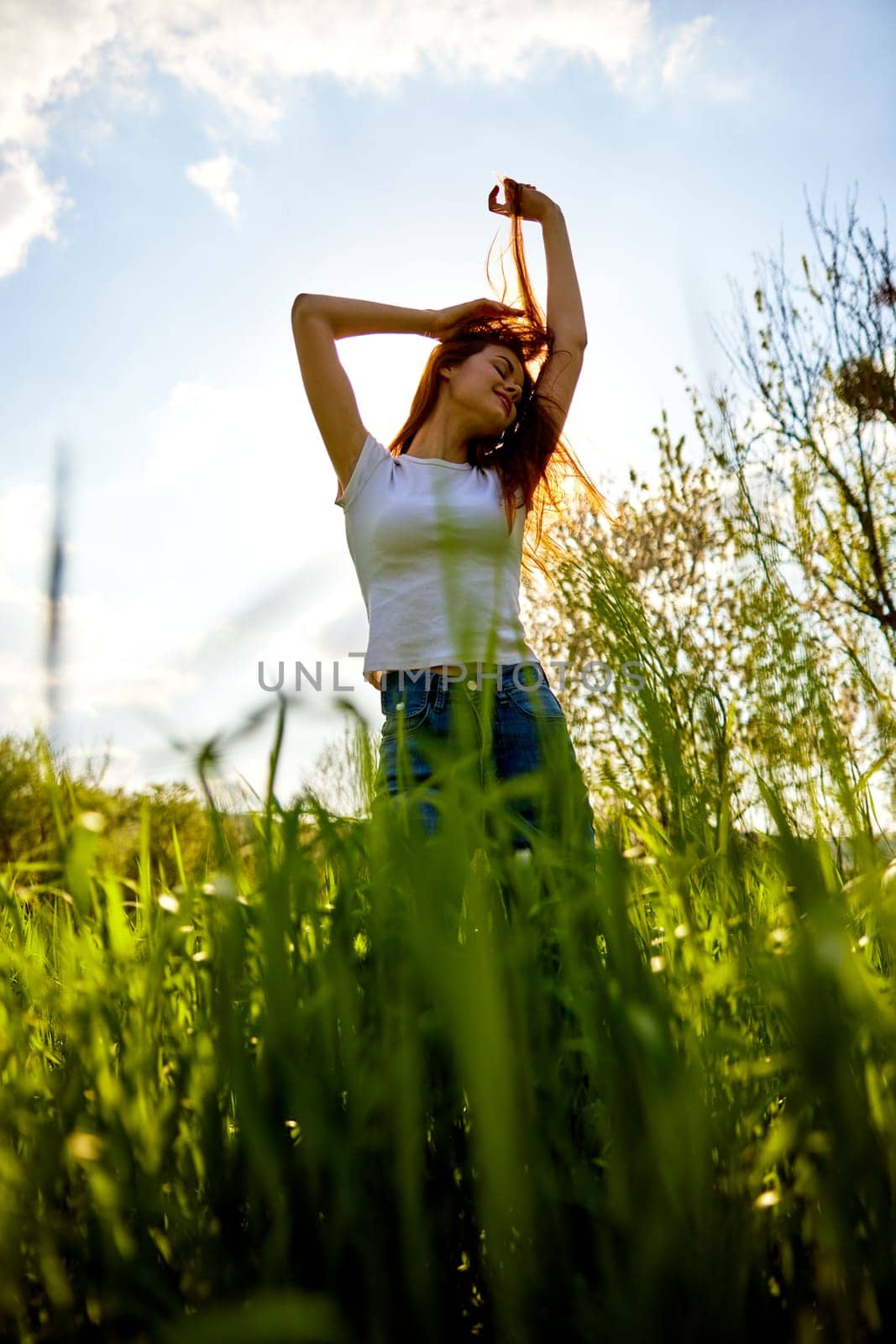 happy woman dancing in high grass field, bottom view. High quality photo