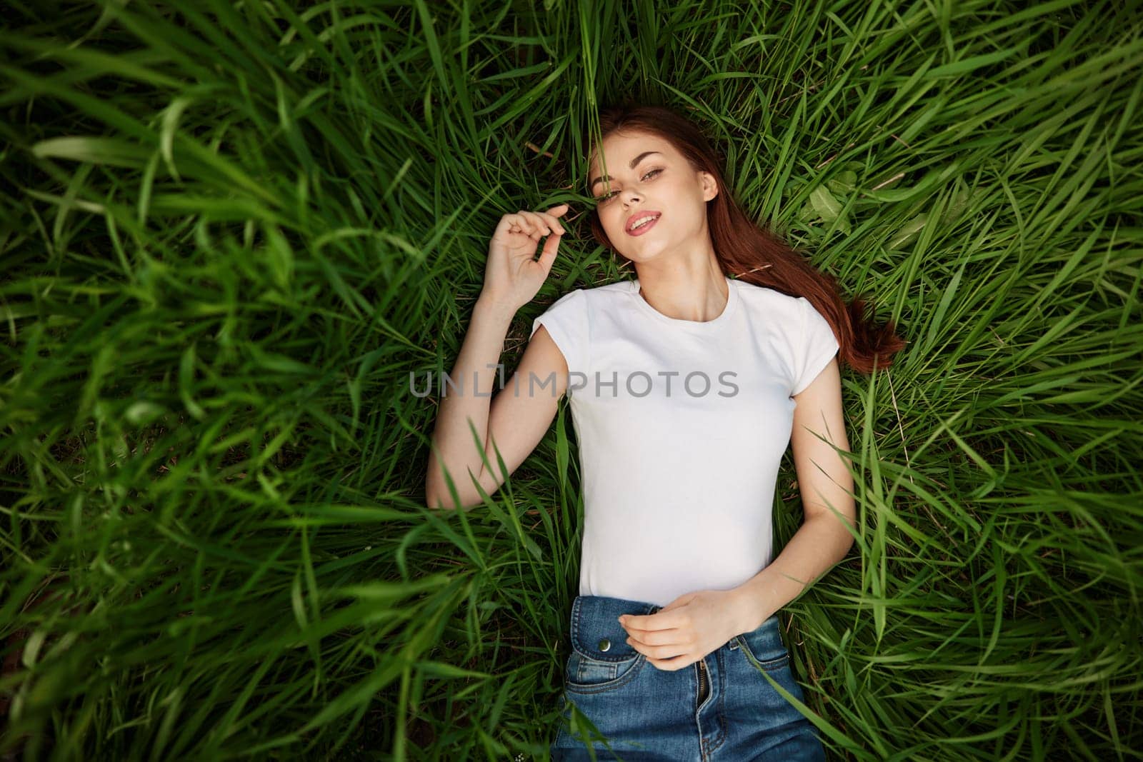 a woman lies in lush, green, tall grass by Vichizh