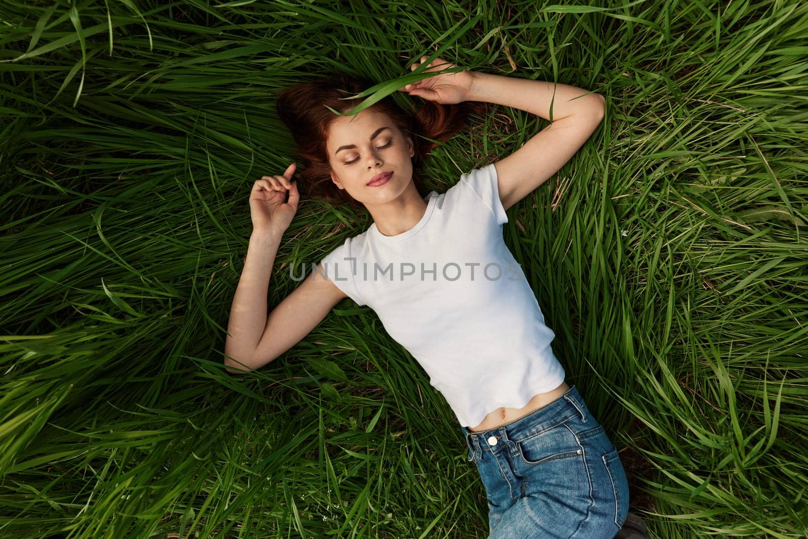 The young woman lies in a green bright grass i. High quality photo