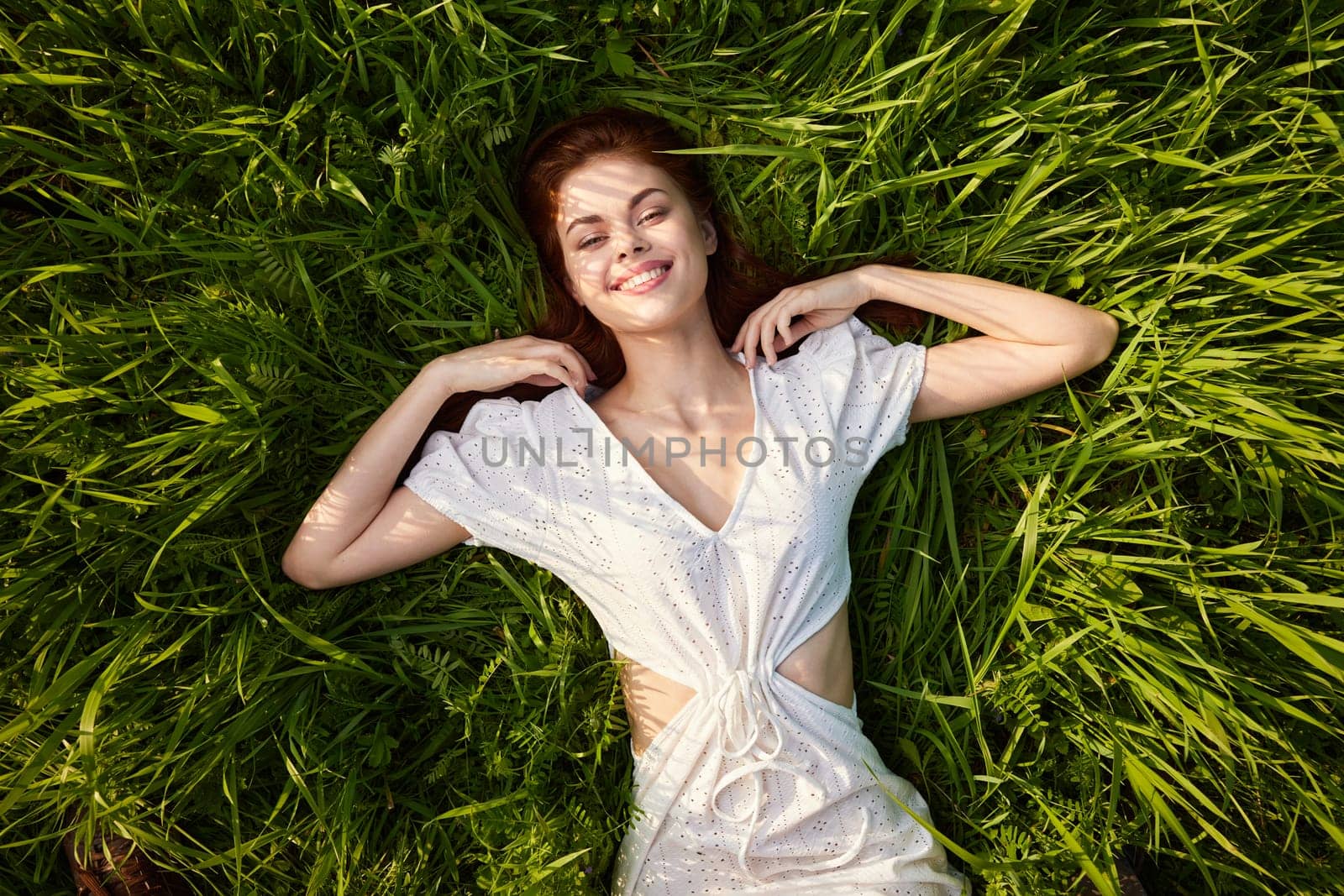 a woman in a white dress is lying on the grass in sunset. High quality photo