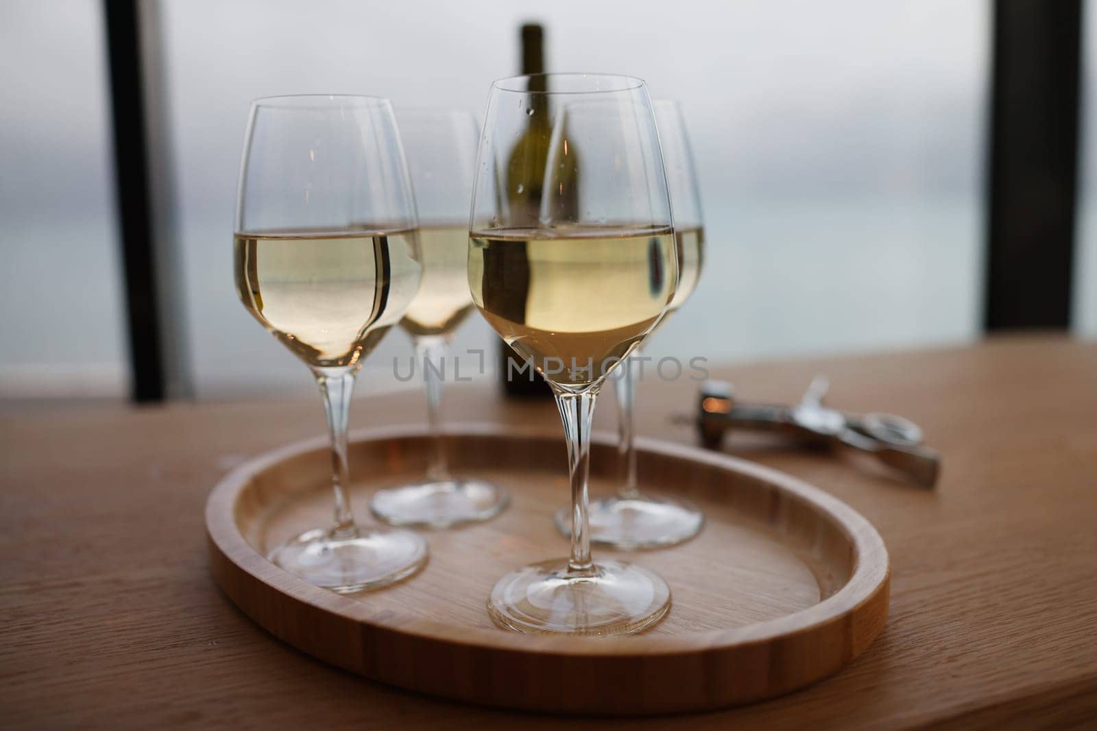 Lot of glasses with white wine and bottle standing on table in restaurant closeup by kuprevich