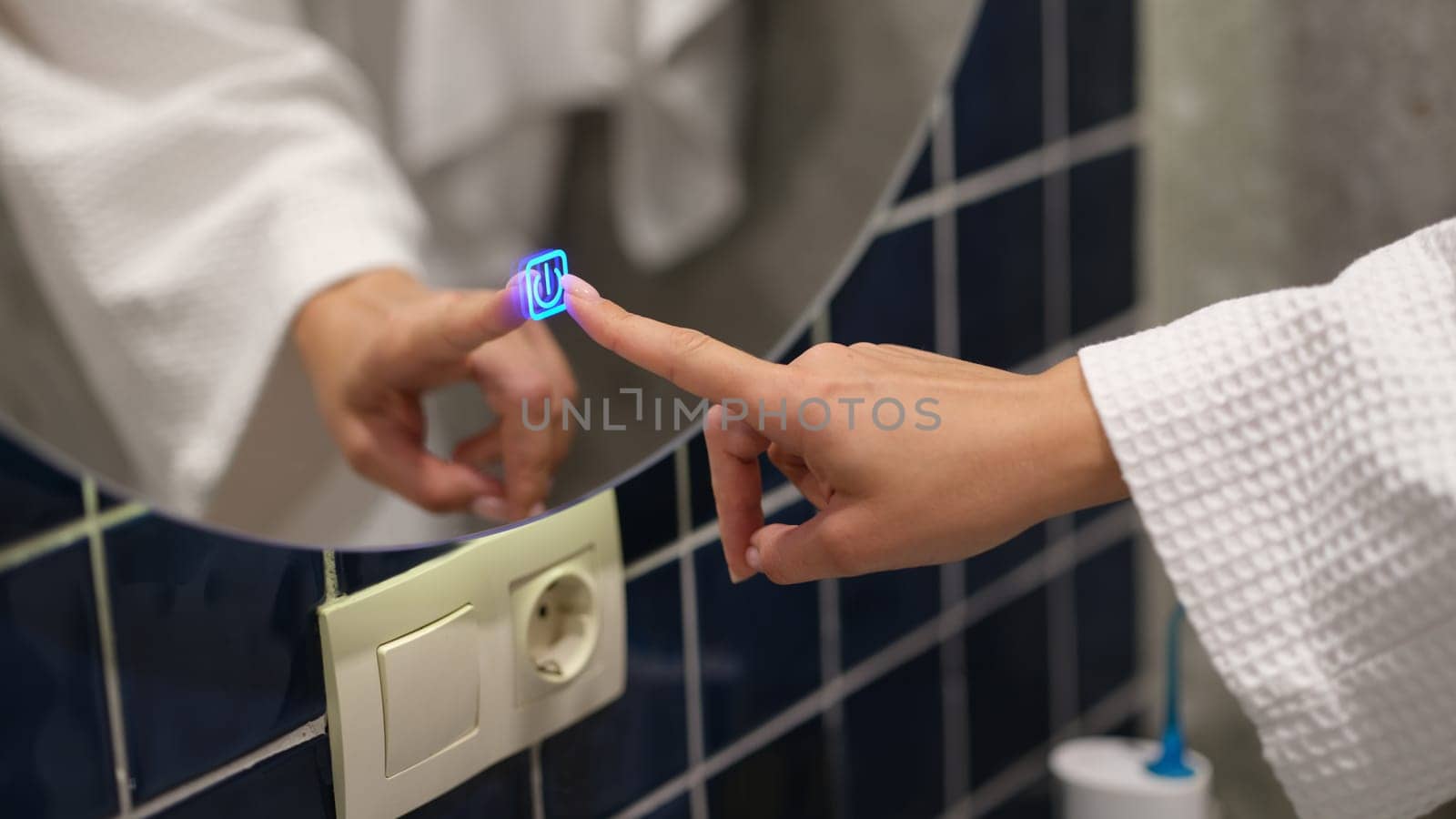 Woman hand pressing button for turning on light and heating mirror in bathroom closeup. Modern home accessories concept