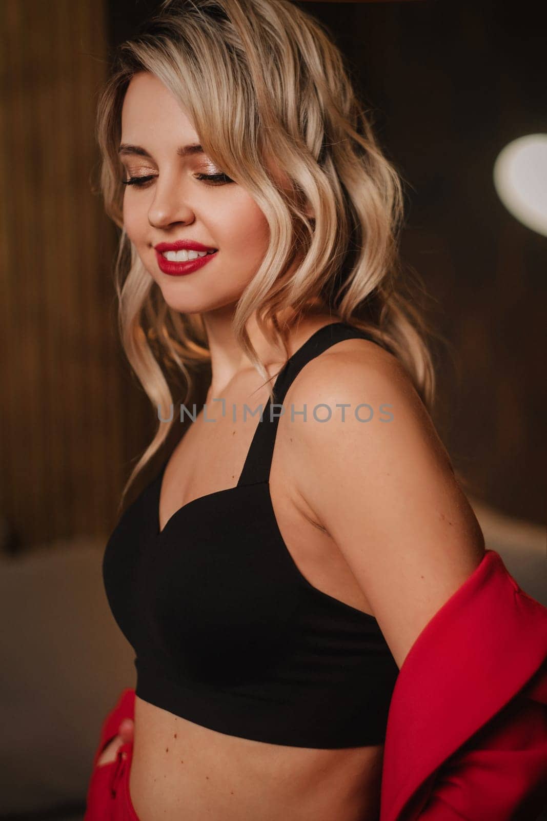 a beautiful girl dressed in a red formal suit posing in a modern interior.