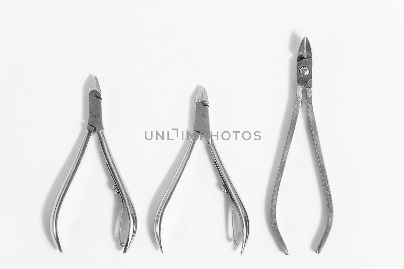 3 different manicure tweezers or nail clippers on a white background.