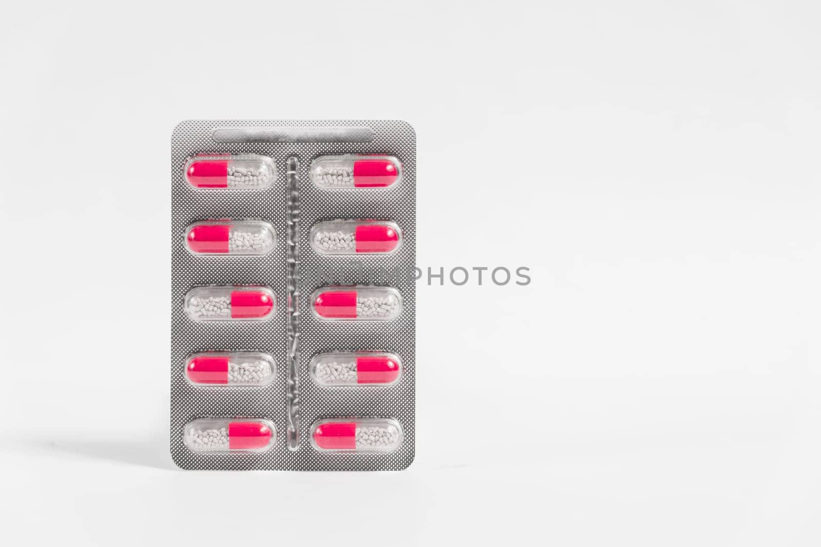 Blister with red pills on white background.
