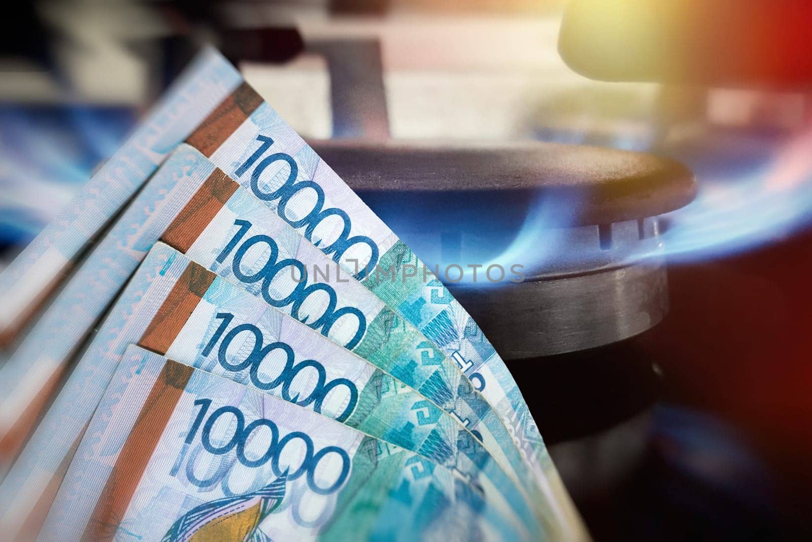 Kazakh money Tenge on the background of a kitchen gas burner. The concept of expensive natural gas.