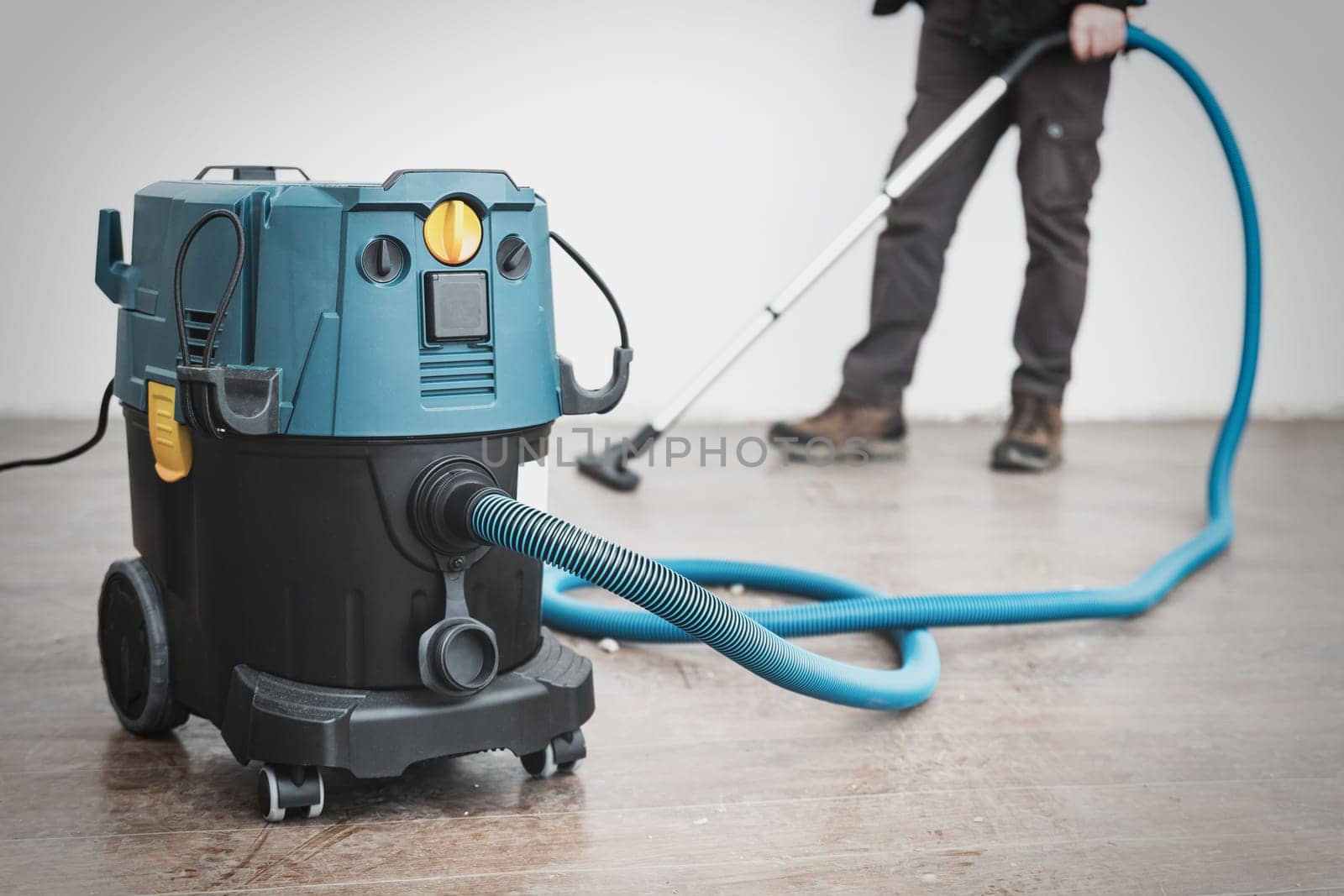 A worker cleans construction debris after repairs with a large construction vacuum cleaner.