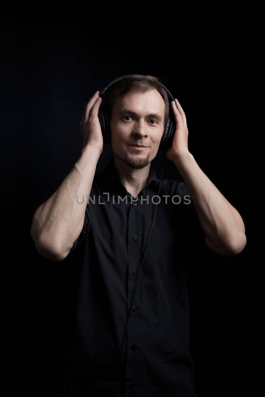 Low key portrait of a man in headphones looking at the camera, copy space.