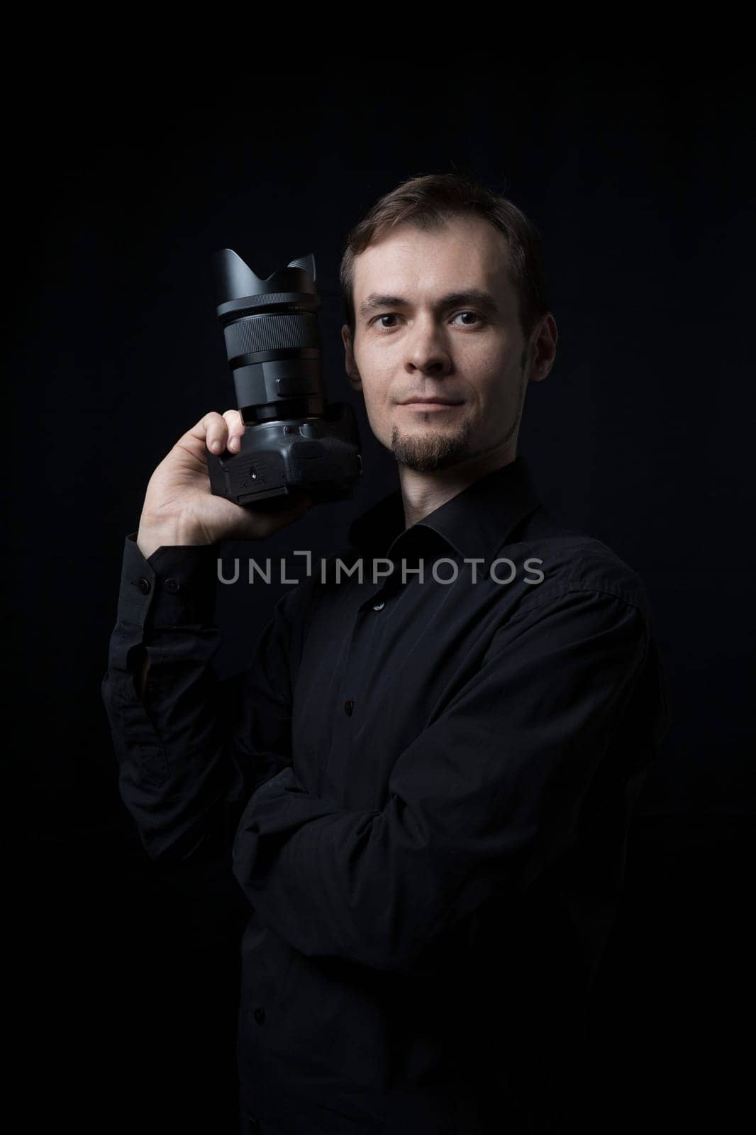 Portrait of a photographer caucasian man with a camera in the dark, copy space.