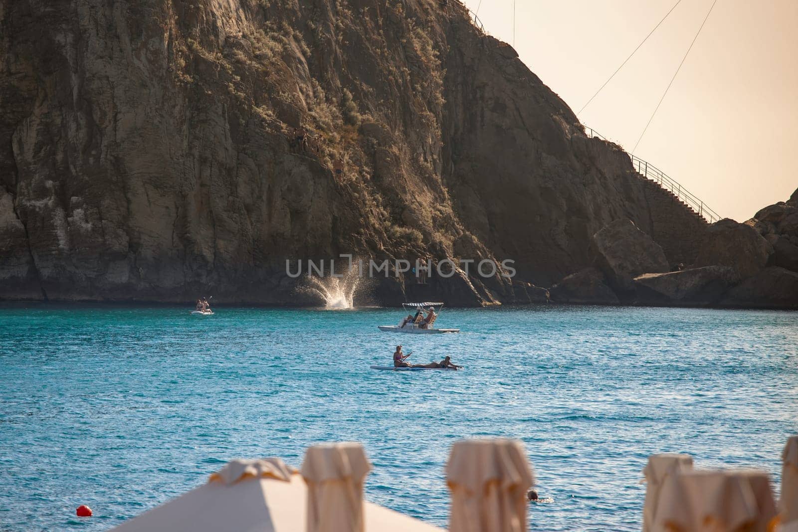 a general view of the bay with turquoise water and unrecognizable people resting against a cliff background. summer vacation.