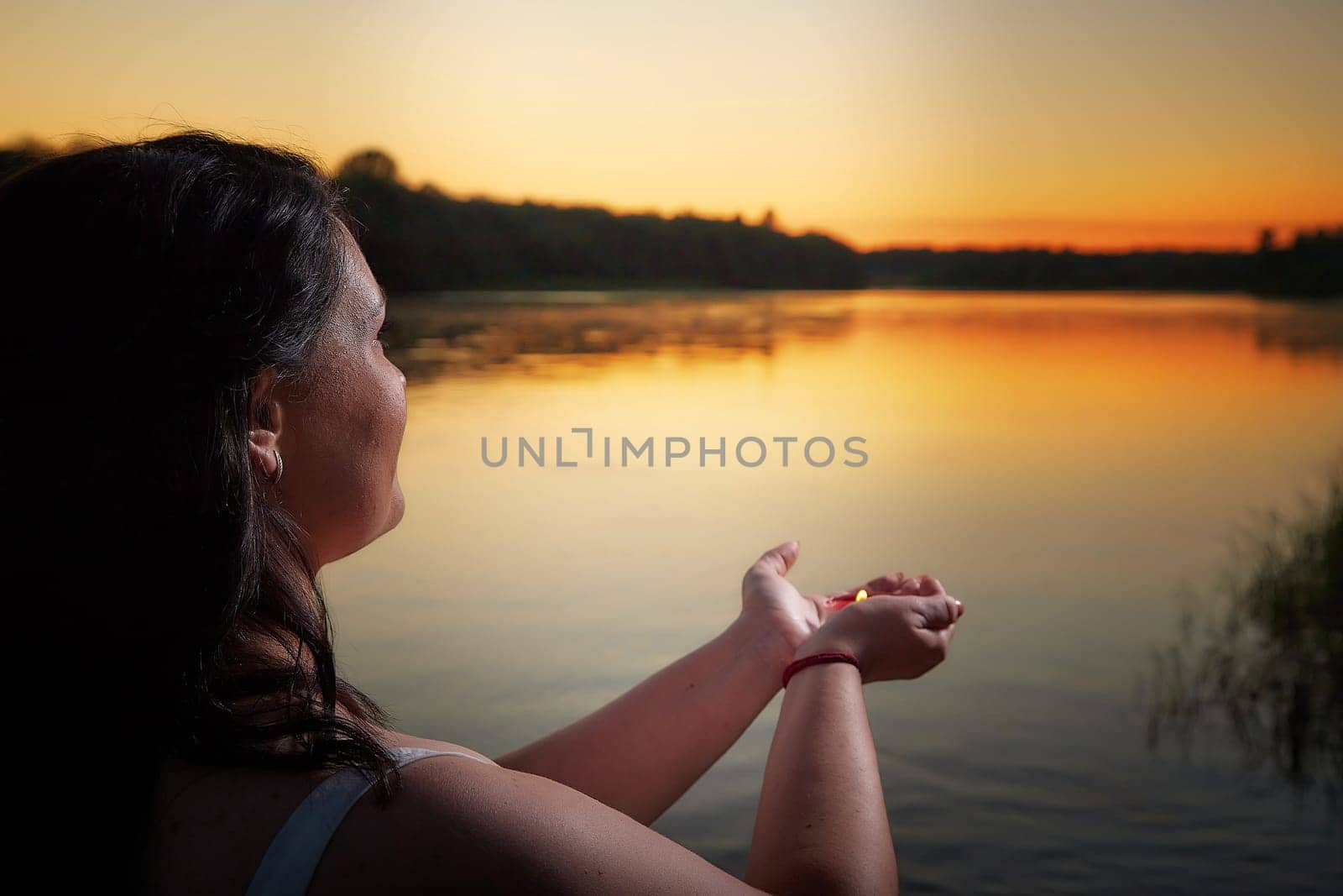 Slavic plump plump chubby girl in long white dress on the feast of Ivan Kupala with flowers and water in a river or lake on summer evening