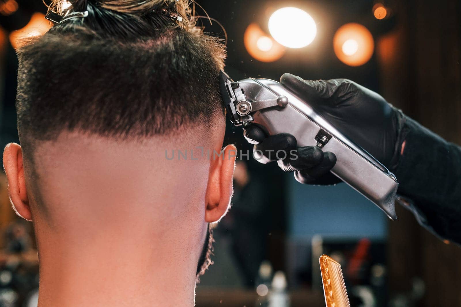 Close up view of young bearded man that sitting and getting haircut in barber shop by Standret
