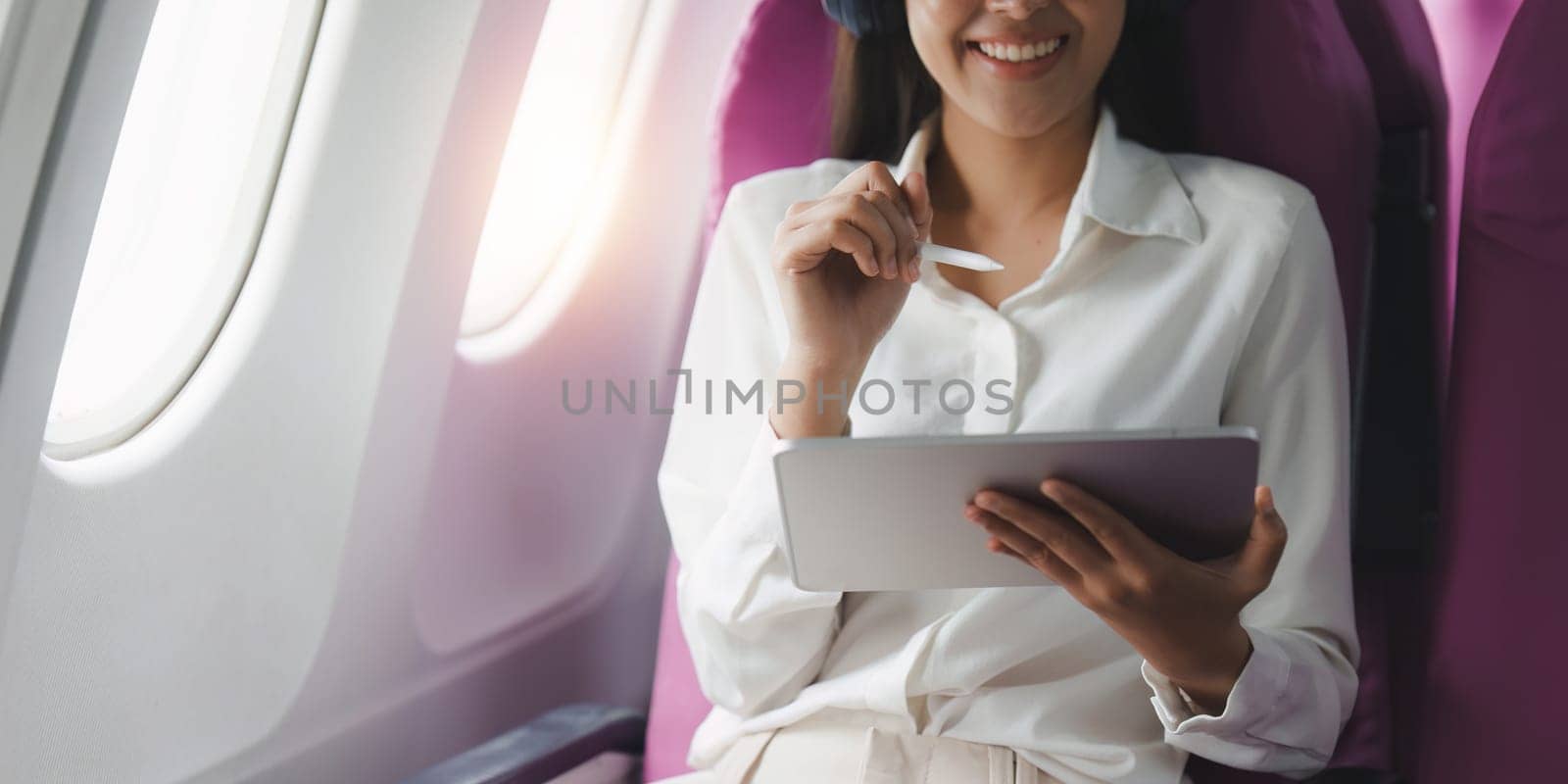 Beautiful Asian businesswoman working with digital tablet in aeroplane. working, travel, business concept.