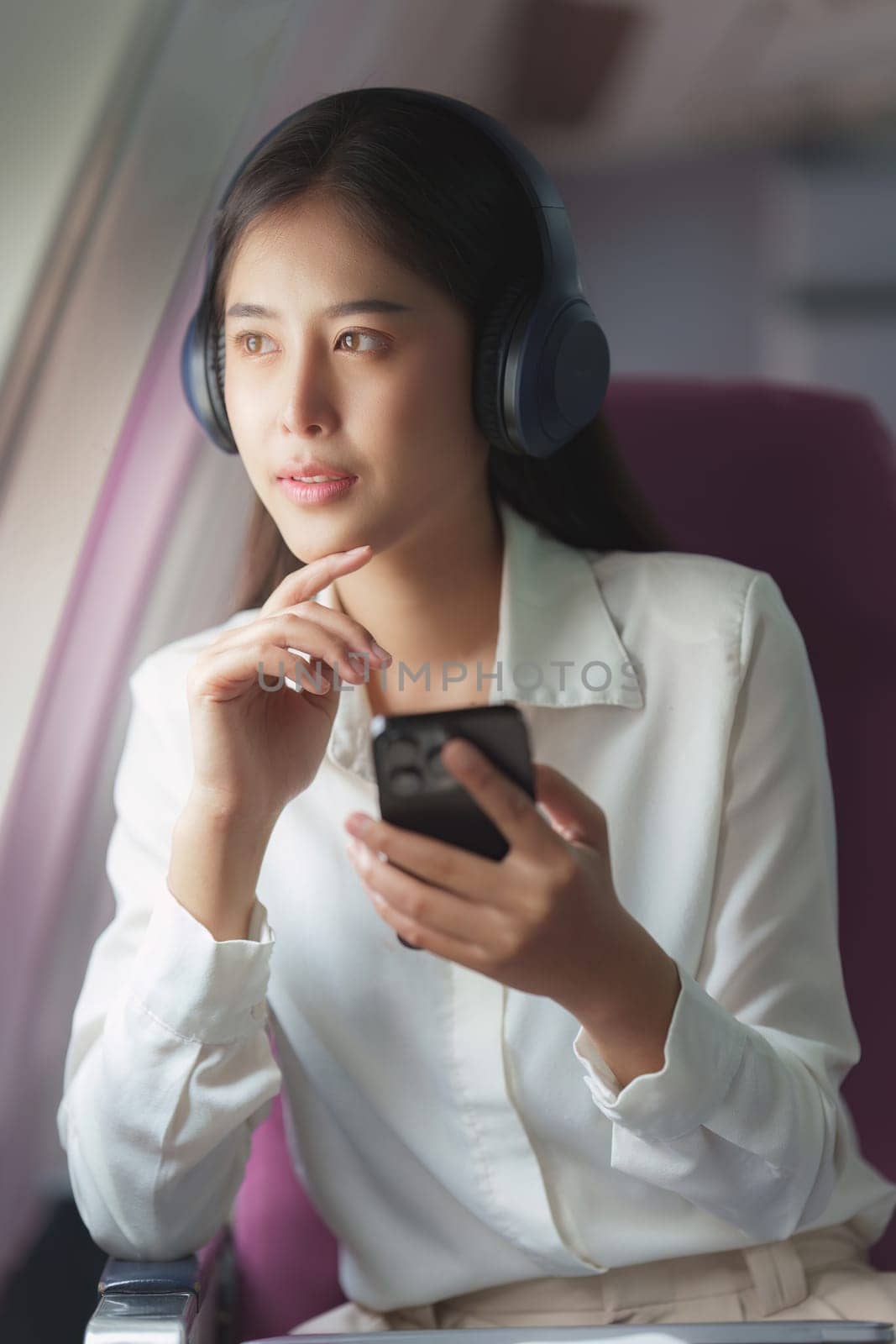 Beautiful Asian business woman listen music by mobile phone during flight in aeroplane. working, travel, business concept by itchaznong
