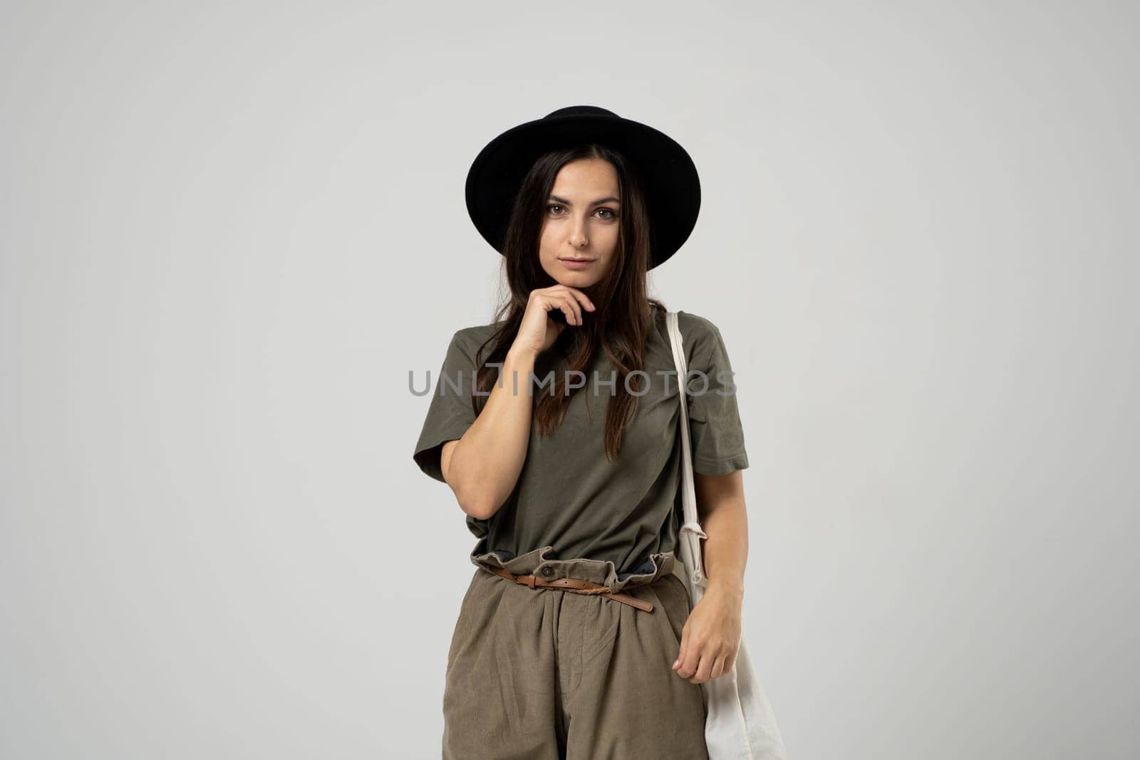 Happy smiling brunette woman in black hat with white cotton eco bag on her shoulder. Girl holding textile grocery bag with vegetables. Zero waste concept. by vovsht