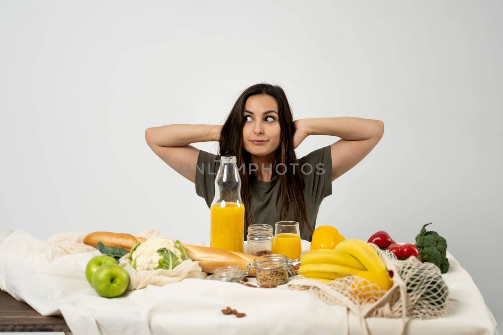 Happy woman in green t-shirt with a mesh eco bag with healthy vegan vegetables, fruits, bread and snacks. Healthy eating vegetarian concept