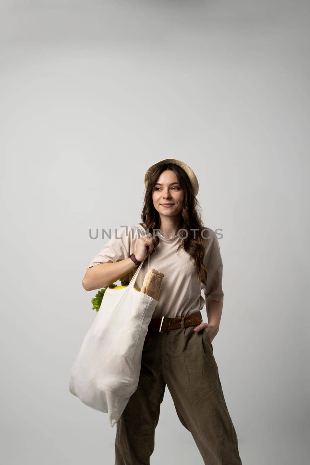 Zero waste concept. Young brunette woman holding mesh eco bag with organic fruits and vegetables. Using reusable crochet net bag for grocery shopping