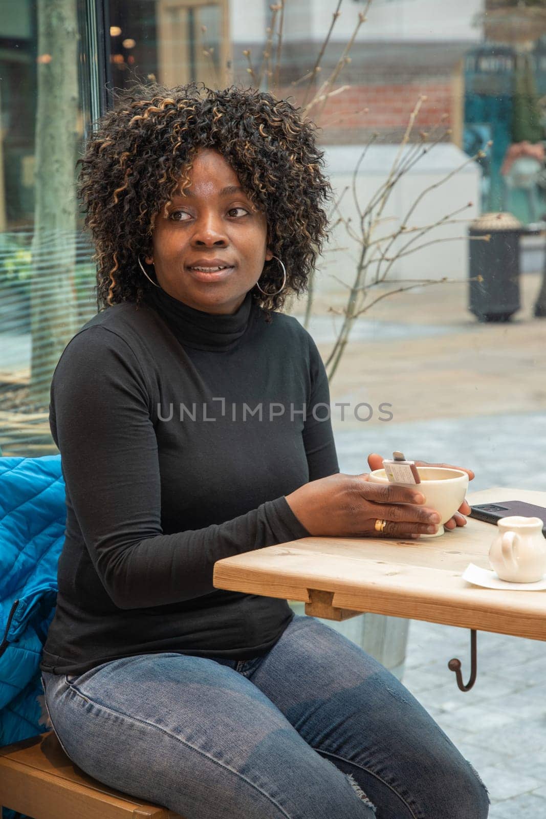 African american woman without makeup sits in a cafe in the morning by KaterinaDalemans