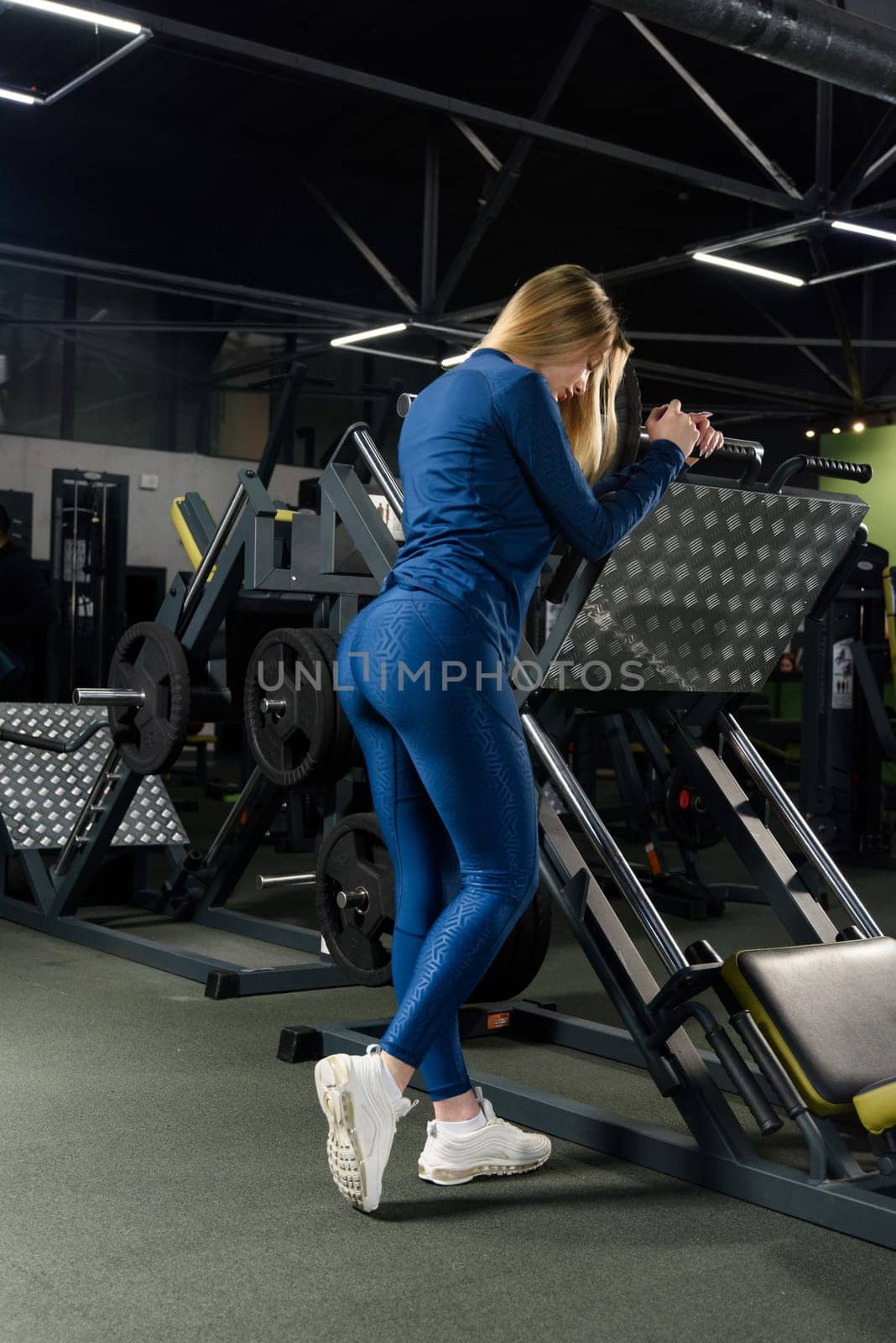 Photo of sporty caucasian woman poses in a gym . wearing blue leggins and long sleeve top