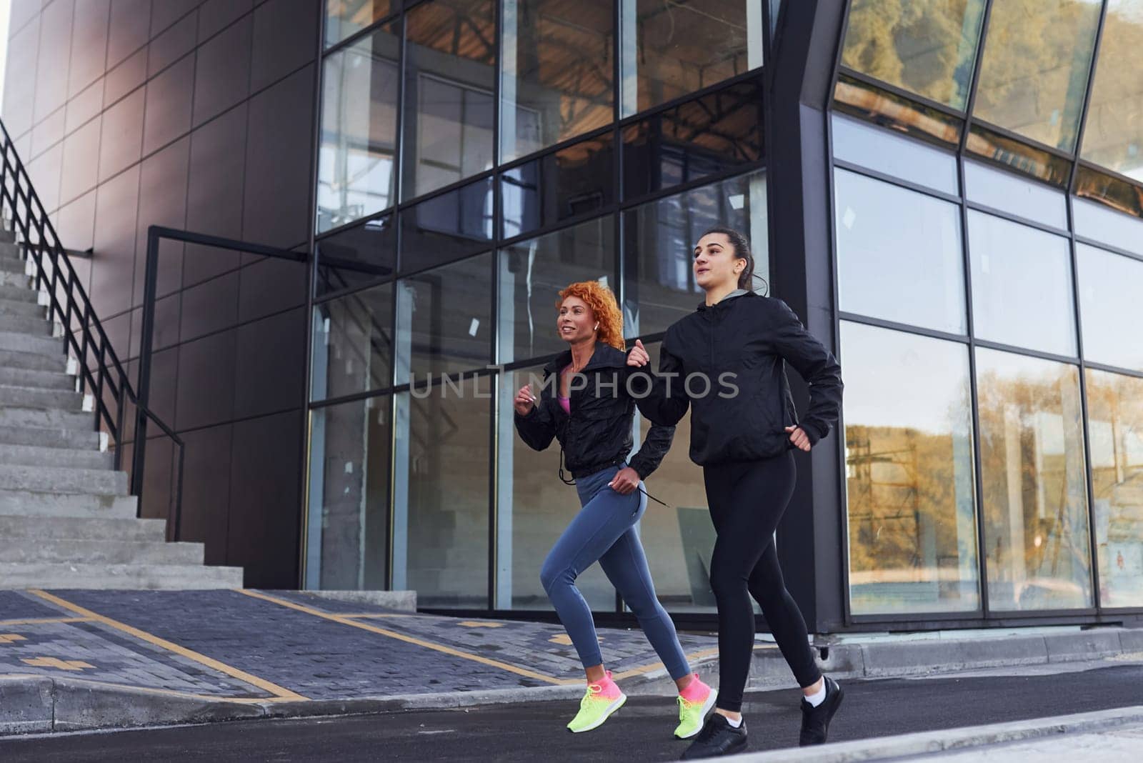 Two female friends with sportive bodies have fitness day outdoors.