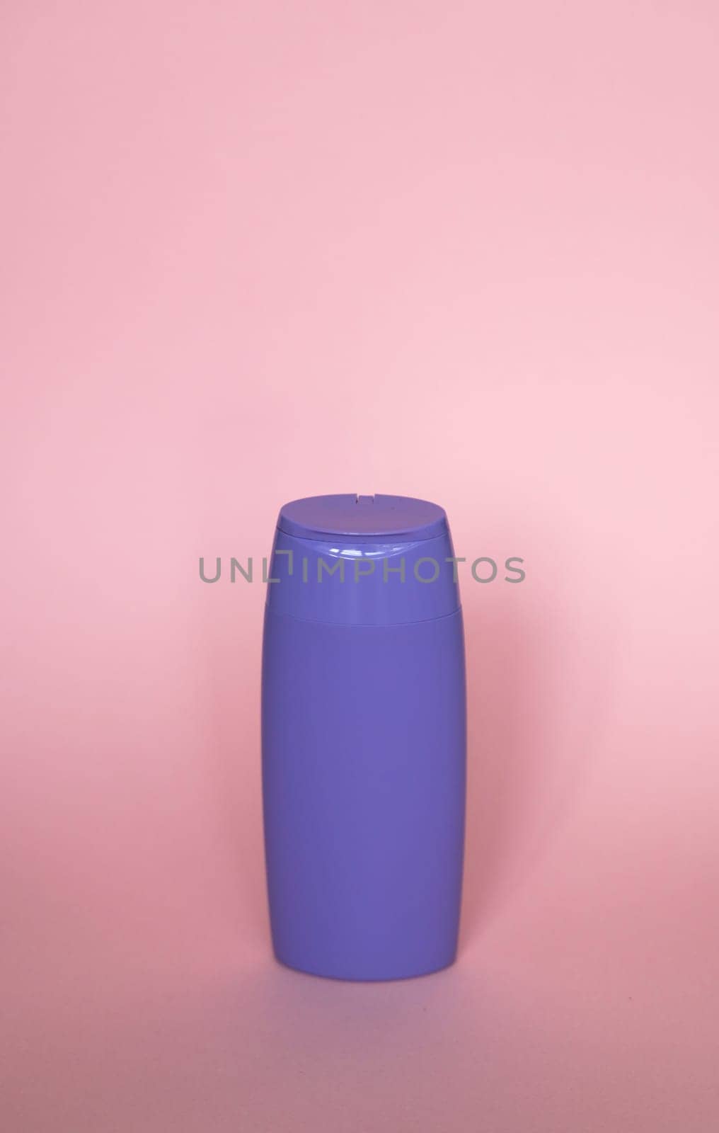 Violet blank unbranded cosmetic plastic bottle for shampoo, gel, lotion, cream, bath foam pink background