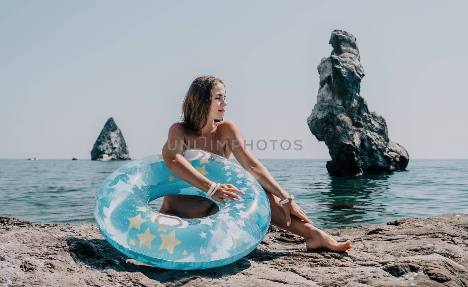 Woman summer sea. Happy woman swimming with inflatable donut on the beach in summer sunny day, surrounded by volcanic mountains. Summer vacation concept
