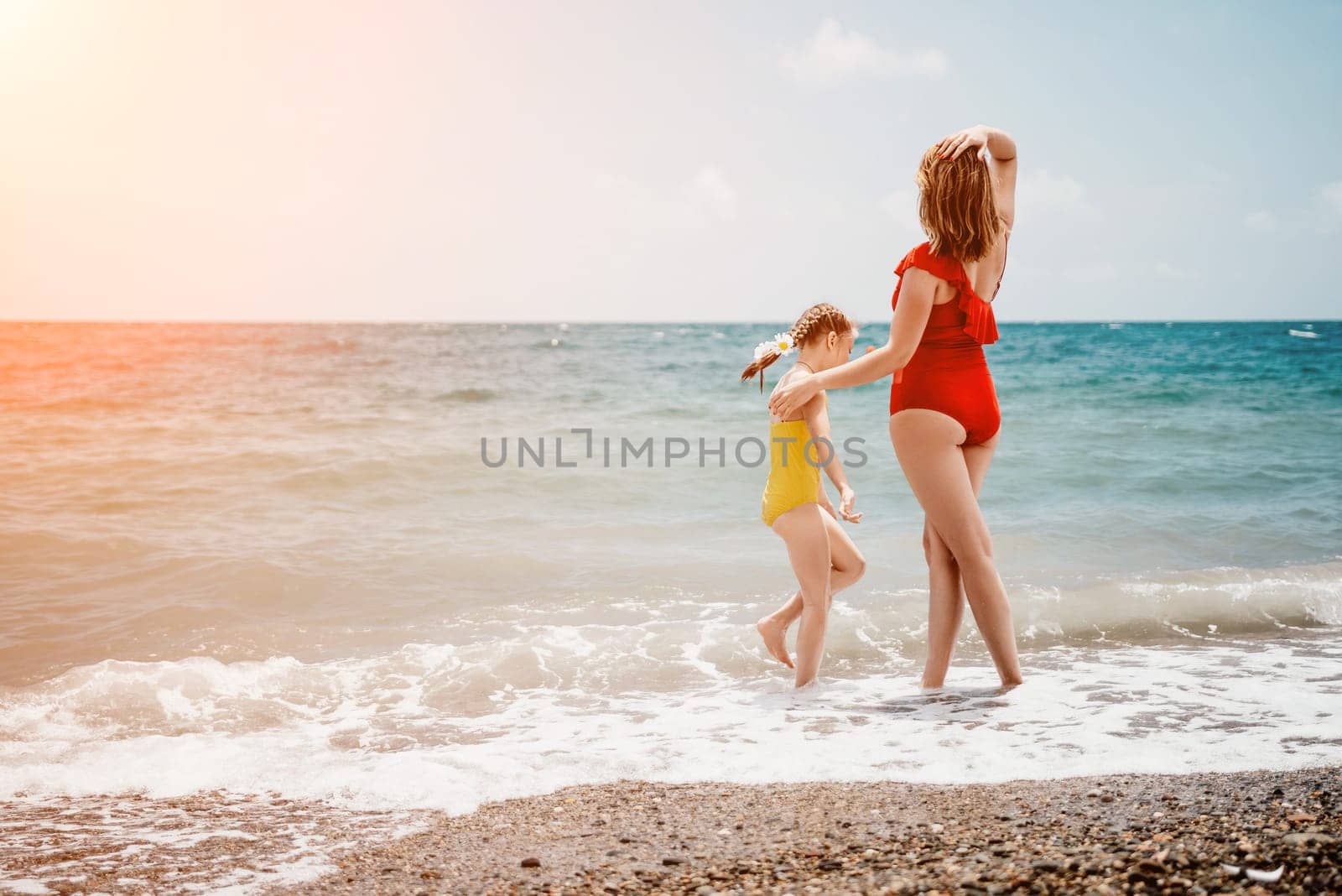 Happy loving family mother and daughter having fun together on the beach. Mum playing with her kid in holiday vacation next to the ocean - Family lifestyle and love concept by panophotograph